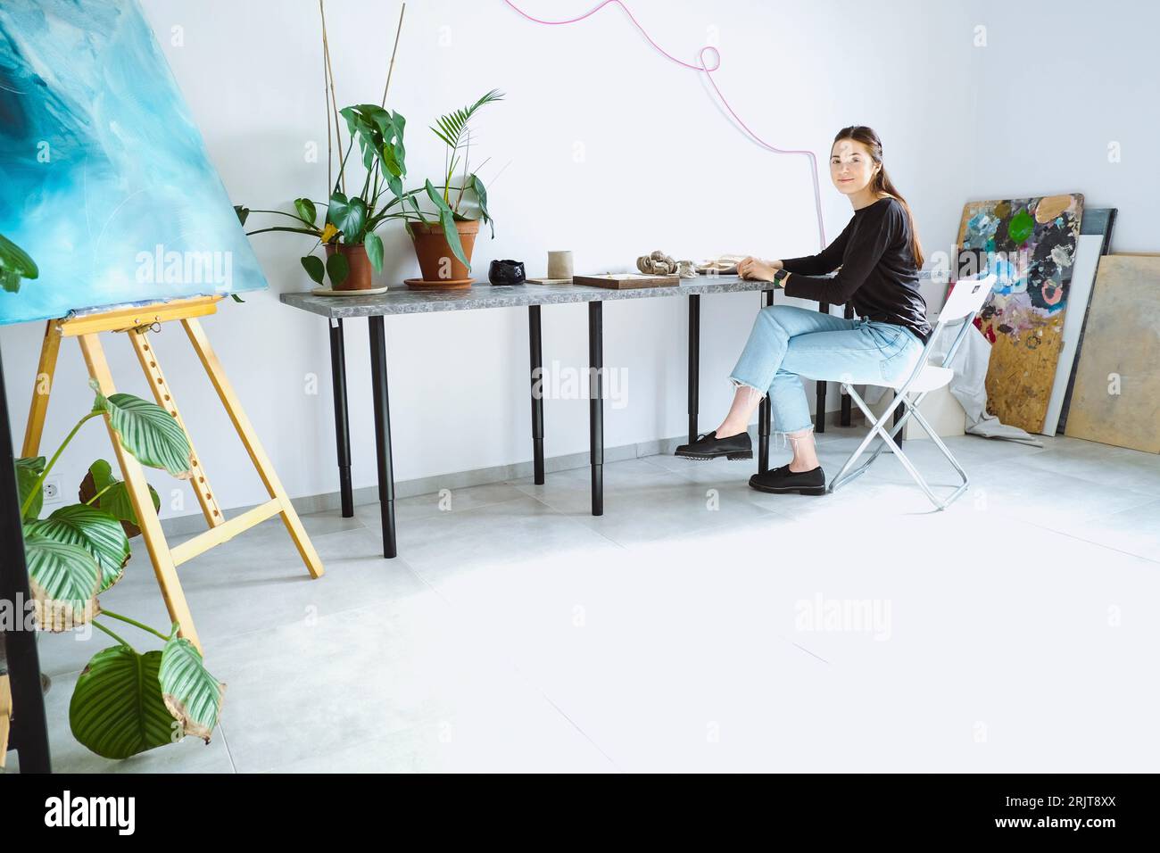 Artista seduto sulla sedia e che lavora in officina Foto Stock