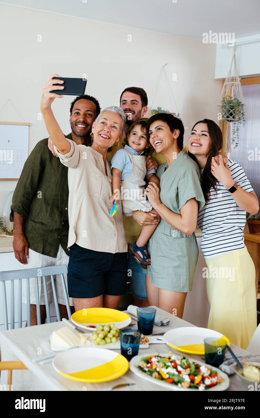 Famiglia felice che scatta selfie con lo smartphone in cucina Foto Stock