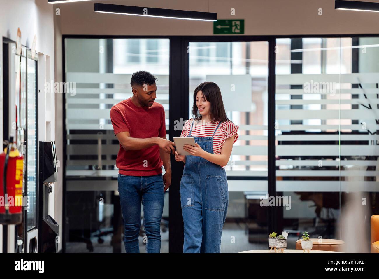 Uomo d'affari che discute con un collega tramite un tablet in ufficio Foto Stock