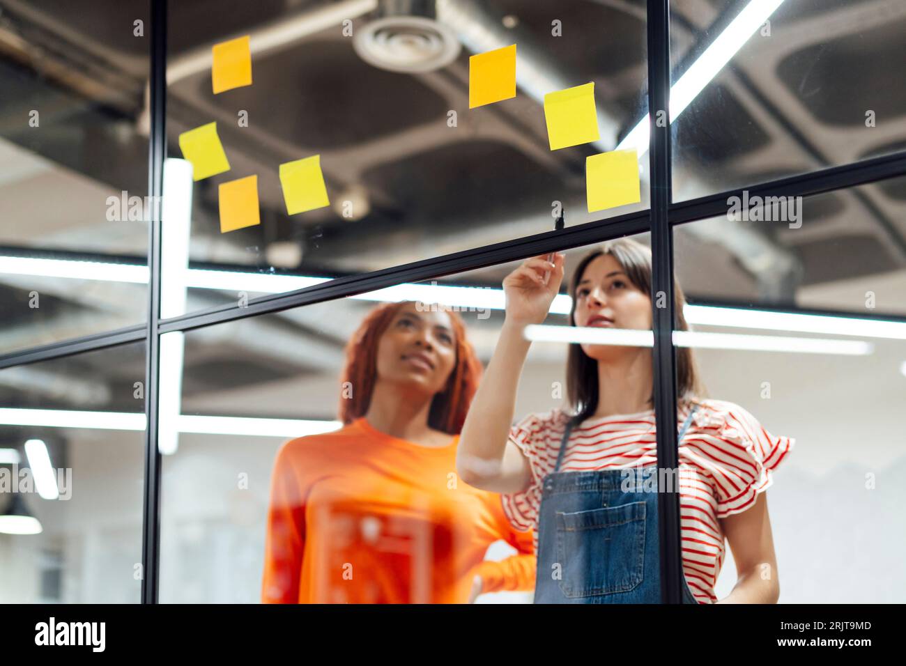 Donne d'affari che pianificano e discutono sulle note adesive in ufficio Foto Stock