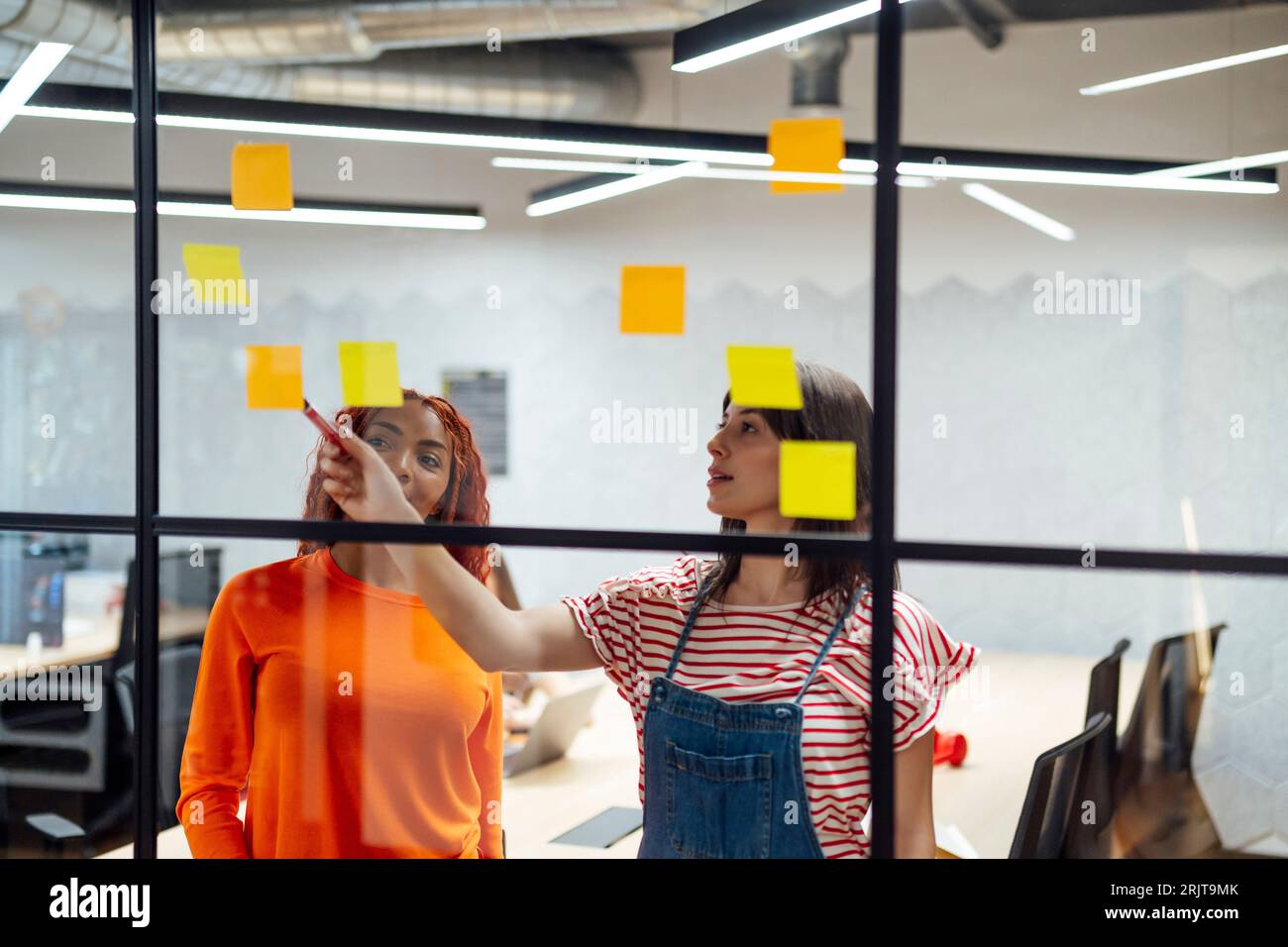 Donne d'affari che discutono sulle note adesive in ufficio Foto Stock