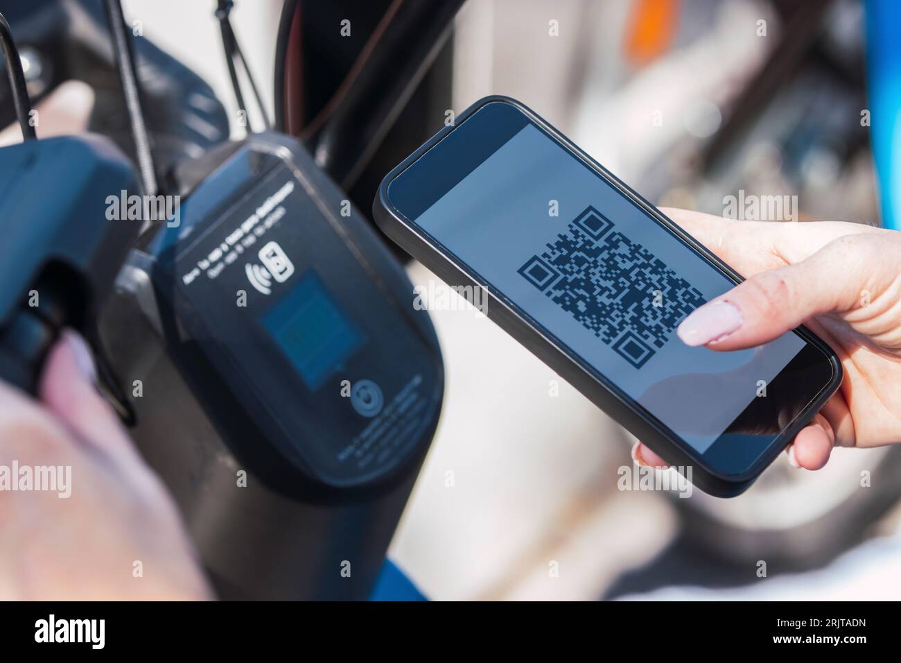 Mani di donna che noleggia biciclette elettriche tramite l'app per telefono cellulare Foto Stock
