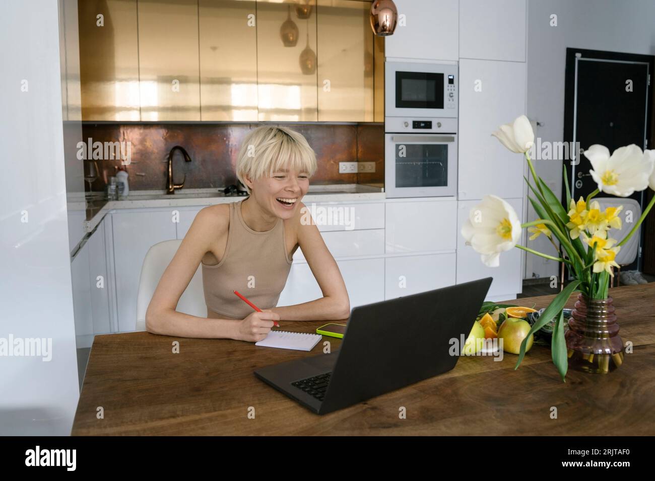 Nutrizionista felice che prende appunti sulla dieta dal portatile a casa Foto Stock