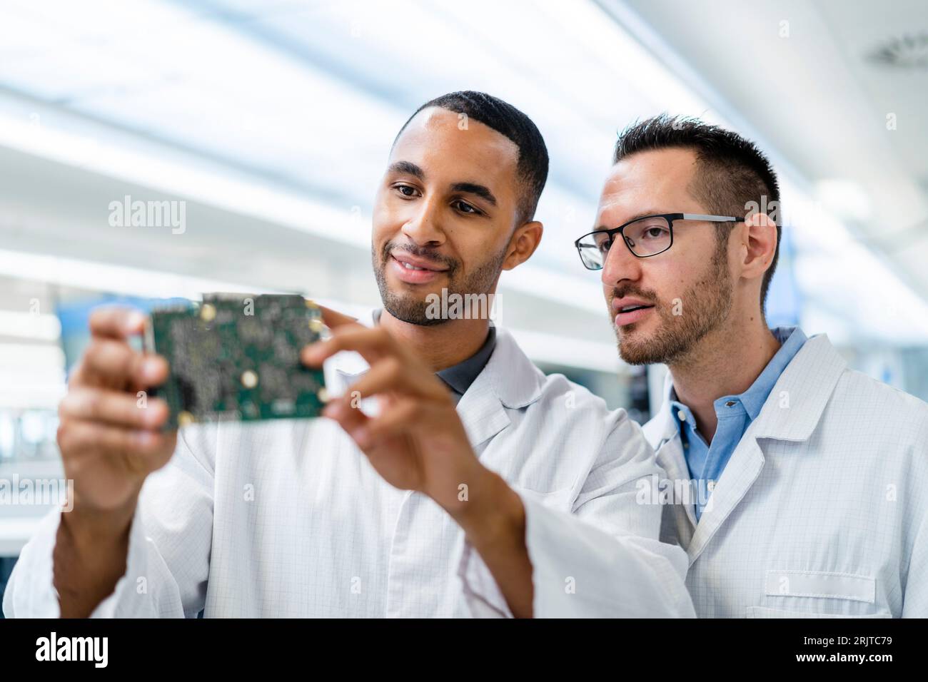 Due colleghi che discutono sulla scheda madre in una fabbrica di elettronica Foto Stock