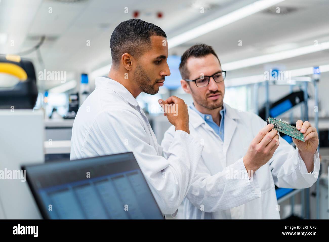 Due colleghi che discutono sulla scheda madre in una fabbrica di elettronica Foto Stock
