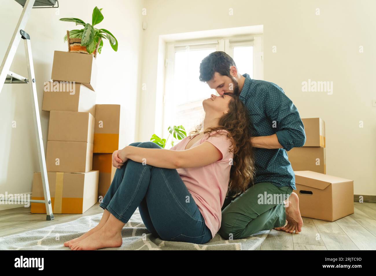 Un uomo romantico che si inginocchiava e baciava la fidanzata nella nuova casa Foto Stock