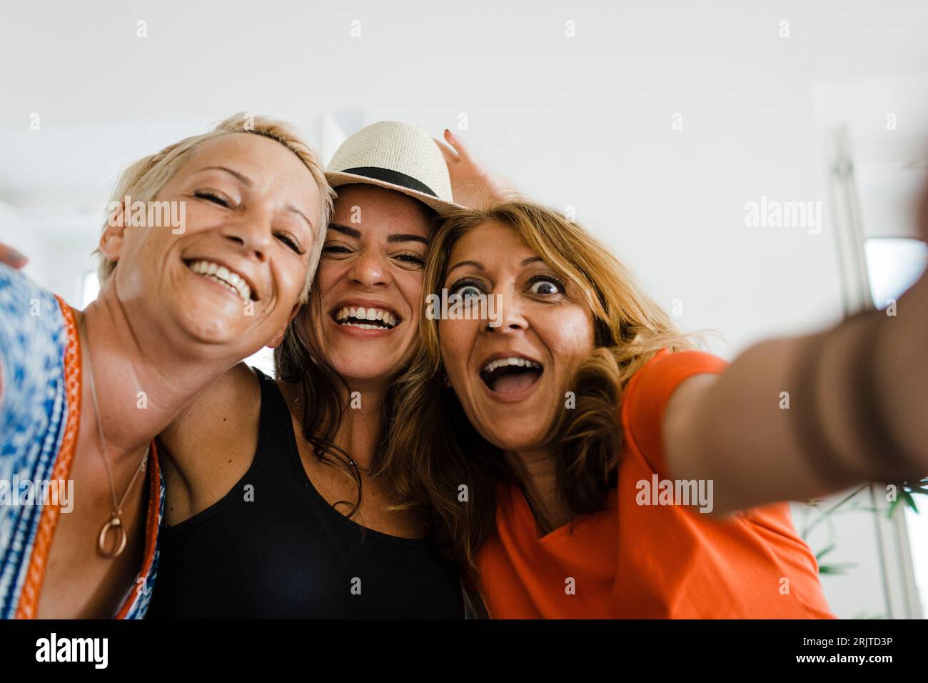Donna allegra che fa selfie con gli amici in appartamento Foto Stock