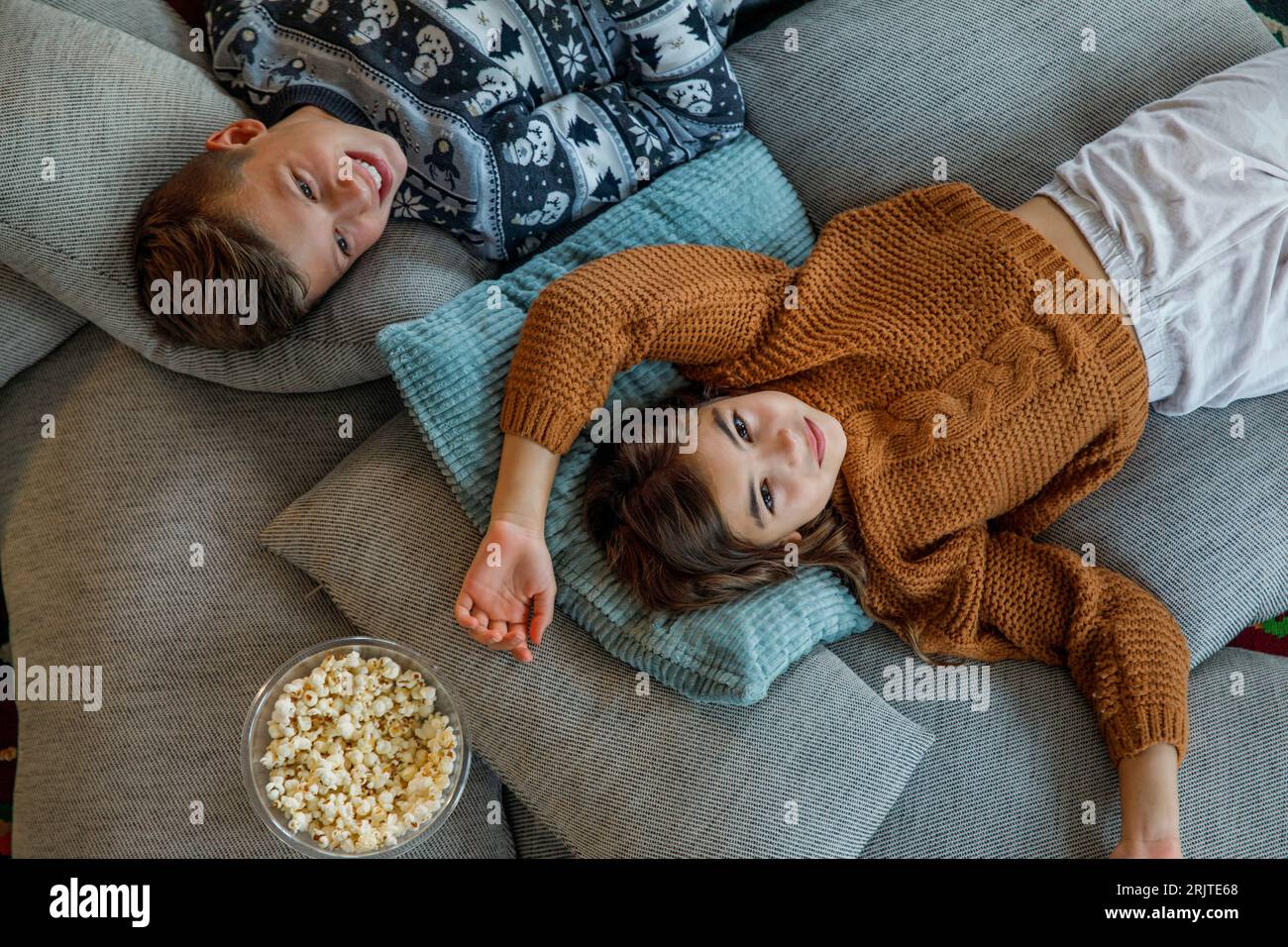 Fratello e sorella riposano sui cuscini a casa Foto Stock