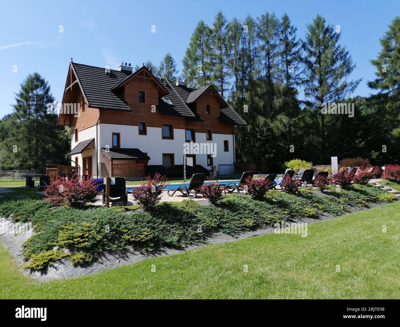 Una bella cabina residenziale vicino a una piscina all'aperto e sedie a sdraio a Szczawnica, Polonia Foto Stock