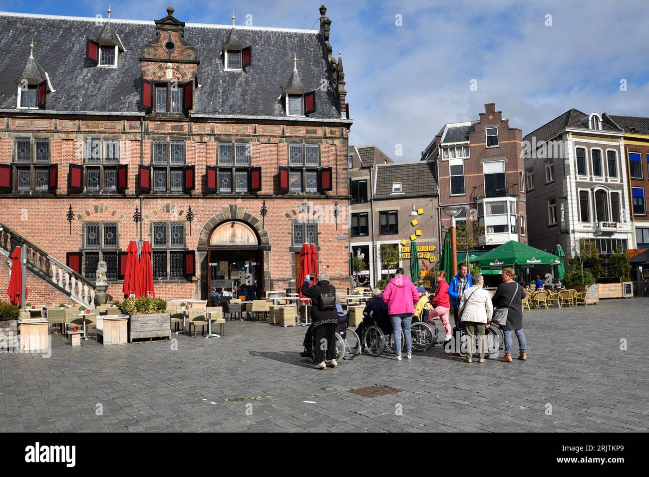 Gli anziani in carrozzina con i loro compagni ammirano l'antica architettura del Boterwaag sul Grote Markt a Nijmegen Foto Stock