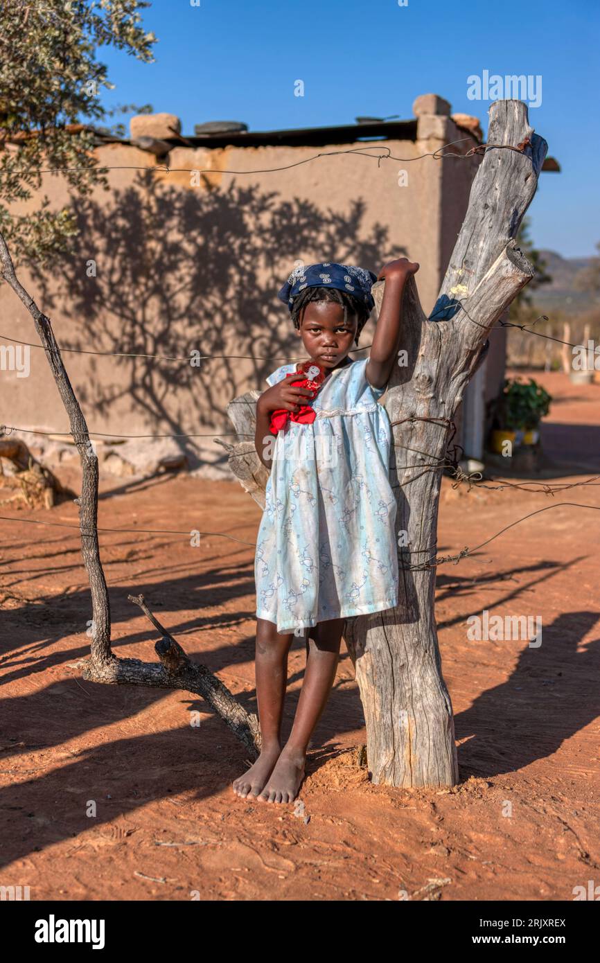 Bambino africano nel villaggio, che gioca con un burattino sulla strada sterrata di fronte alla casa Foto Stock