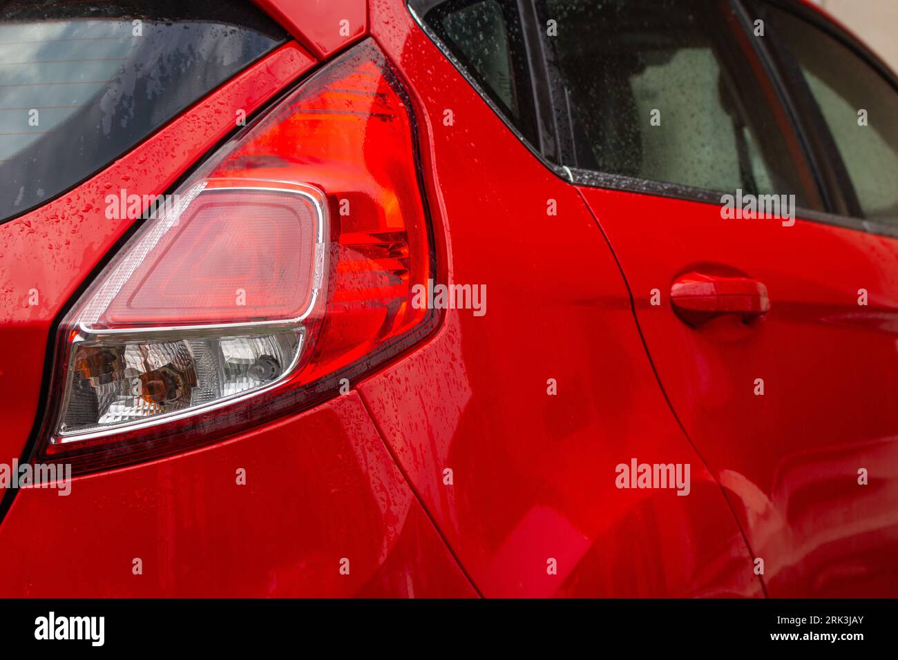Auto rossa con luci di posizione posteriori. Parcheggio auto nel cortile posteriore. Berlina rossa. Trasporto urbano. Concetto di viaggio. Parcheggio auto moderno. Parcheggio automatico. Foto Stock