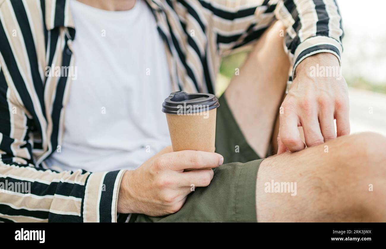 Tazza di carta con coperchio nero in mano all'uomo. Primo piano, tazza di caffè, mockup. concetto da asporto. Foto Stock