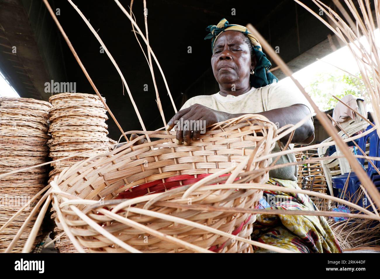 Una donna intreccia un cesto domestico nel più grande villaggio di canne della Nigeria a Mende, nel Maryland District di Lagos. L'artigianato della canna da zucchero in Nigeria, il paese più popoloso dell'Africa, sta prosperando in mezzo a una crisi economica che ha colpito le piccole imprese e i guadagni delle persone. Nel villaggio, decine di persone, tra cui familiari e disoccupati, sono impegnate nella tessitura di diversi oggetti per la casa come tavoli, cesti, portabicchieri, vasi di fiori con legno di canna proveniente dalla palude regione del Delta del Niger. Lagos, Nigeria. Foto Stock