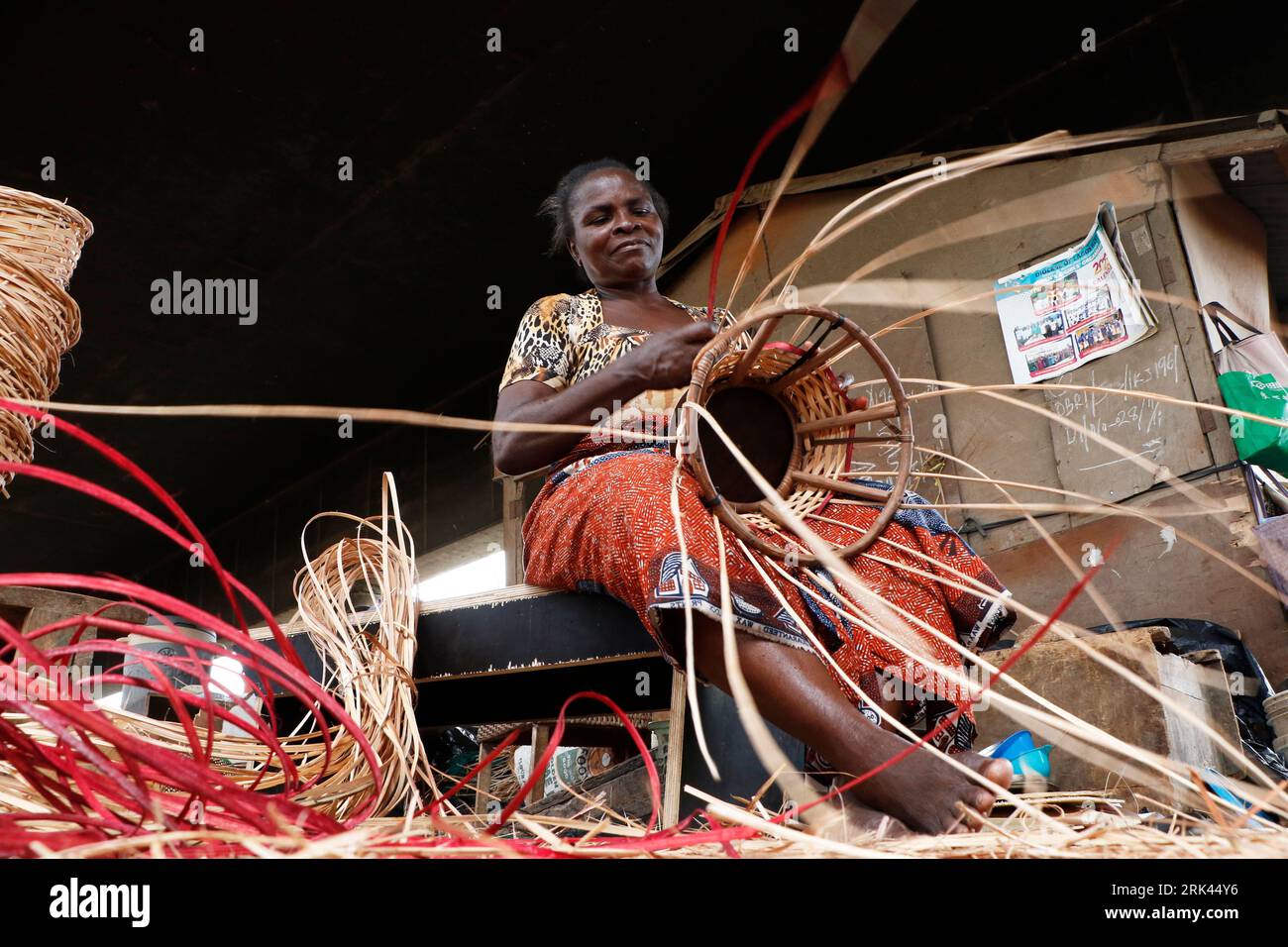 Una donna intreccia un cesto domestico nel più grande villaggio di canne della Nigeria a Mende, nel Maryland District di Lagos. L'artigianato della canna da zucchero in Nigeria, il paese più popoloso dell'Africa, sta prosperando in mezzo a una crisi economica che ha colpito le piccole imprese e i guadagni delle persone. Nel villaggio, decine di persone, tra cui familiari e disoccupati, sono impegnate nella tessitura di diversi oggetti per la casa come tavoli, cesti, portabicchieri, vasi di fiori con legno di canna proveniente dalla palude regione del Delta del Niger. Lagos, Nigeria. Foto Stock