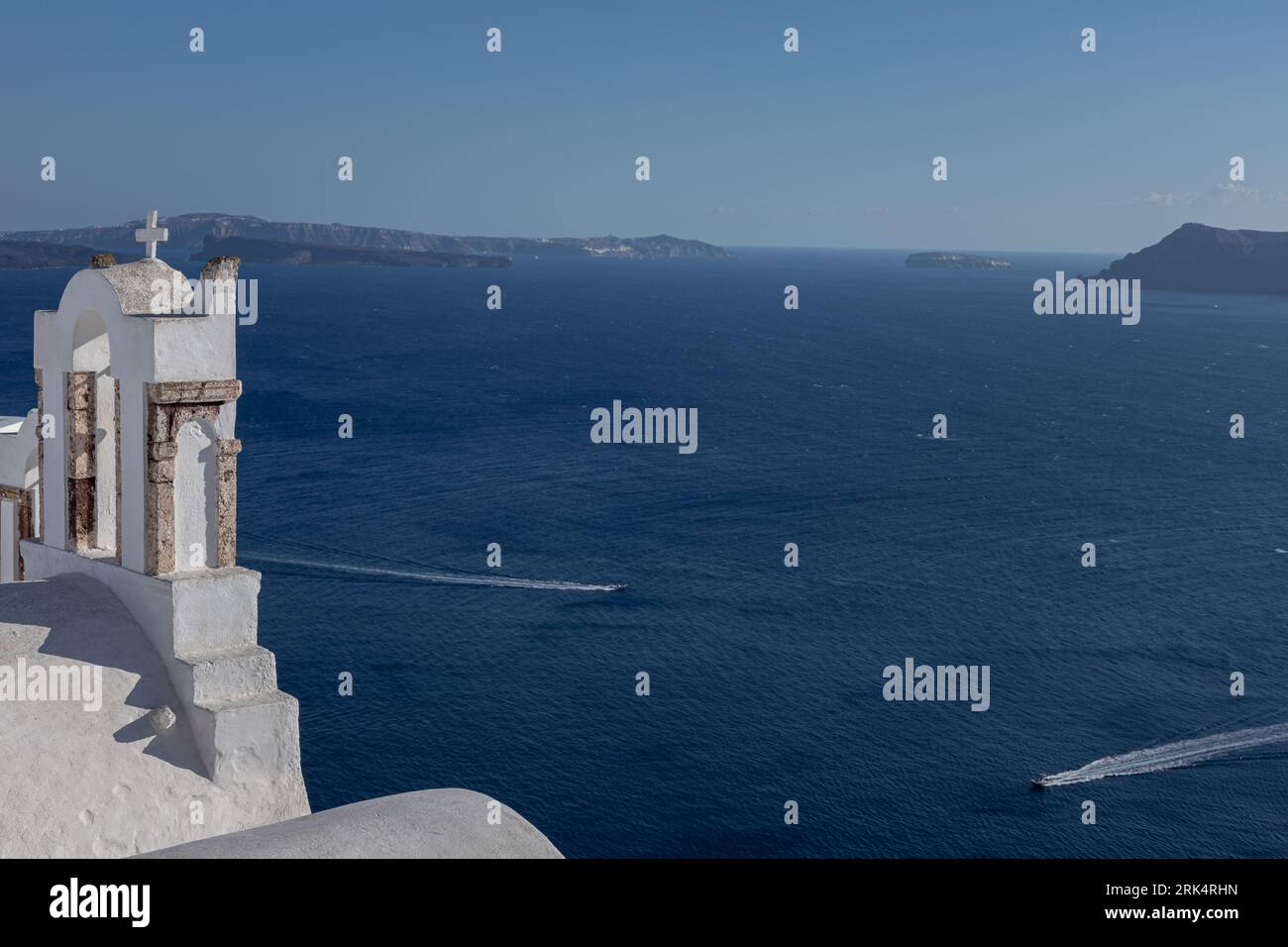 Una torre bianca con una grande finestra che si affaccia su un tranquillo oceano blu a Santorini, in Grecia Foto Stock