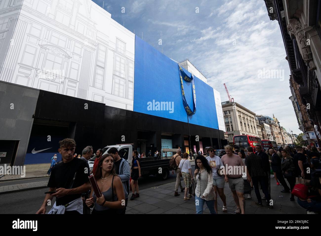 Londra, Regno Unito. 24 agosto 2023. La gente passa davanti a una gigantesca borsa per lo shopping IKEA che è stata svelata sulla costruzione esterna che circonda l'ex ammiraglia Top Shop di Oxford Circus. IKEA sta progettando di aprire un negozio in città in quel luogo nell'autunno 2024 (precedentemente previsto per l'autunno 2023). I commentatori hanno affermato che Oxford Street, una volta la via dello shopping più trafficata d’Europa, ha bisogno di un impulso tanto necessario. Crediti: Stephen Chung / Alamy Live News Foto Stock