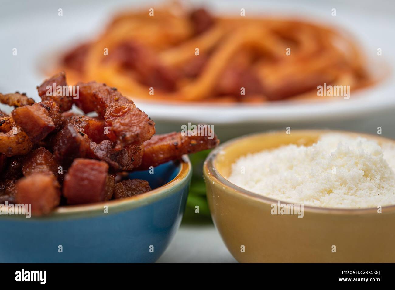 Bucatini fatti in casa all'Amatriciana, guance di manzo cotte su pasta, formaggio e salsa di pomodoro in un recipiente bianco Foto Stock