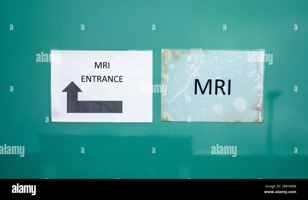 Un cartello cartaceo con la scritta "MRI" accanto a un altro cartello cartaceo con la scritta "MRI Entrance" con una grande freccia direzionale attaccata sul lato di una RM mobile privata Foto Stock