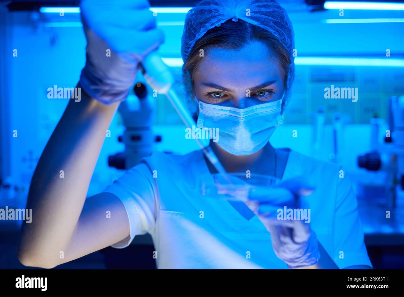 L'embriologo in una maschera protettiva manipola il biomateriale Foto Stock