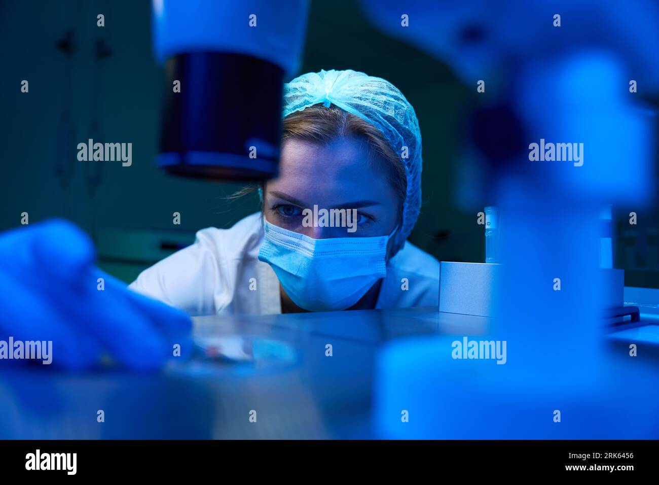 L'assistente di laboratorio in una maschera protettiva conduce una procedura ICSI Foto Stock