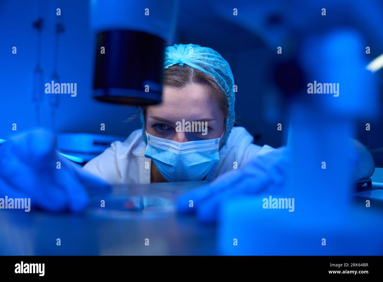 Il giovane assistente di laboratorio lavora con i biomateriali in un laboratorio sterile Foto Stock