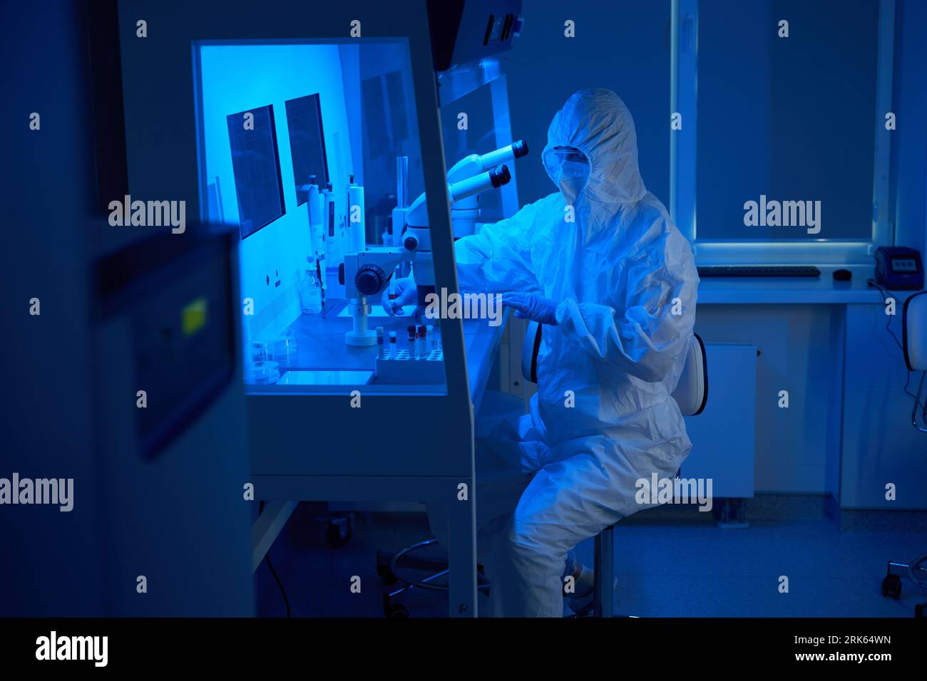 Un uomo in uniforme sterile usa un set di micromanipolatori Foto Stock