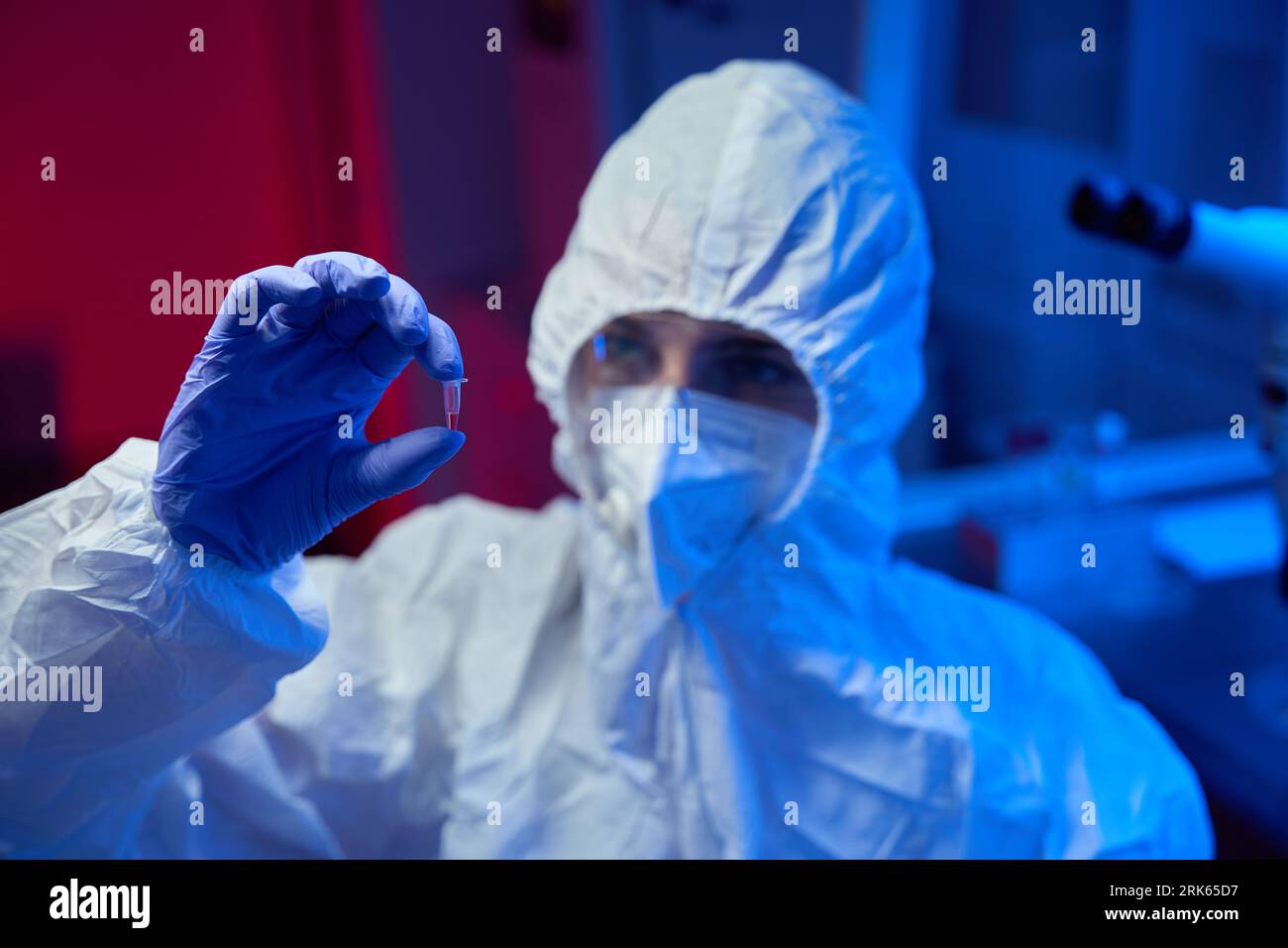 L'assistente di laboratorio in uniforme protettiva contiene una provetta Foto Stock