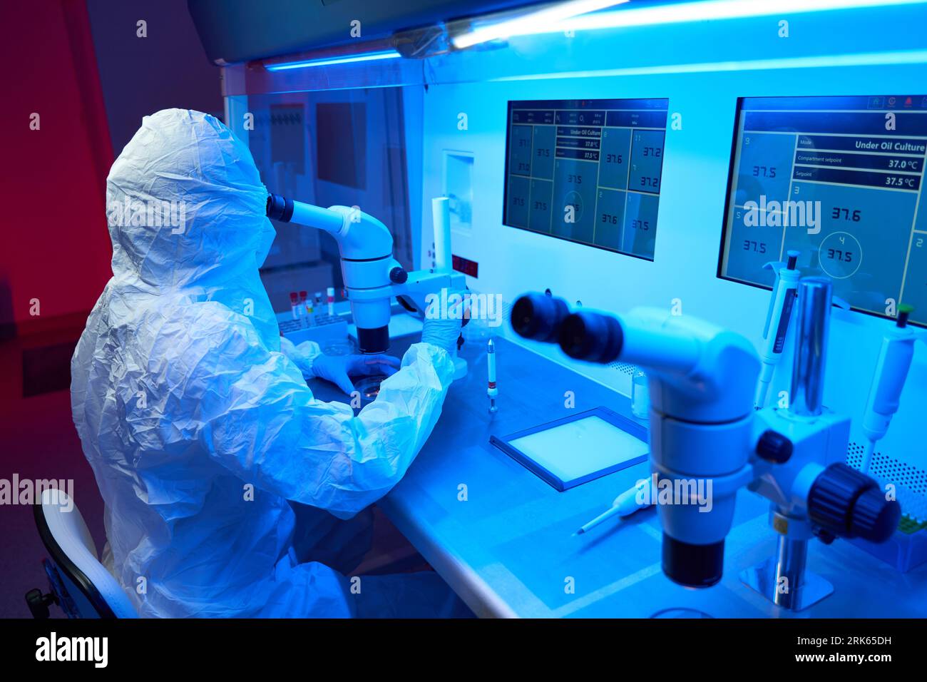 L'operatore di laboratorio in uniforme protettiva esegue una procedura ICSI Foto Stock