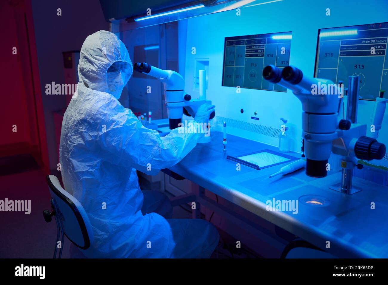 L'embriologo in uniforme protettiva esegue la procedura ICSI Foto Stock
