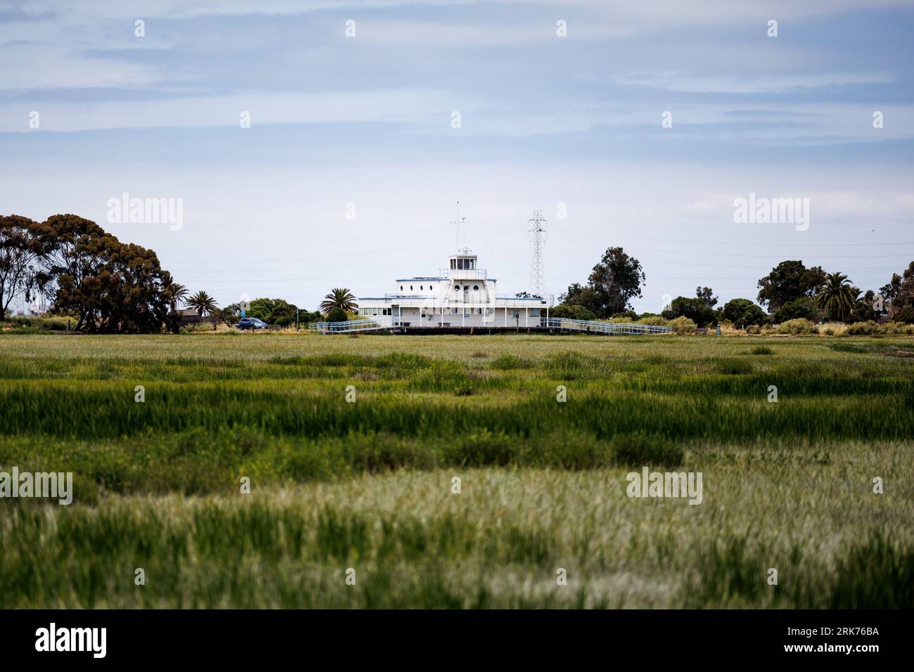 Un grande edificio bianco situato su una pianura erbosa sulla costa, circondato da un paesaggio aperto Foto Stock