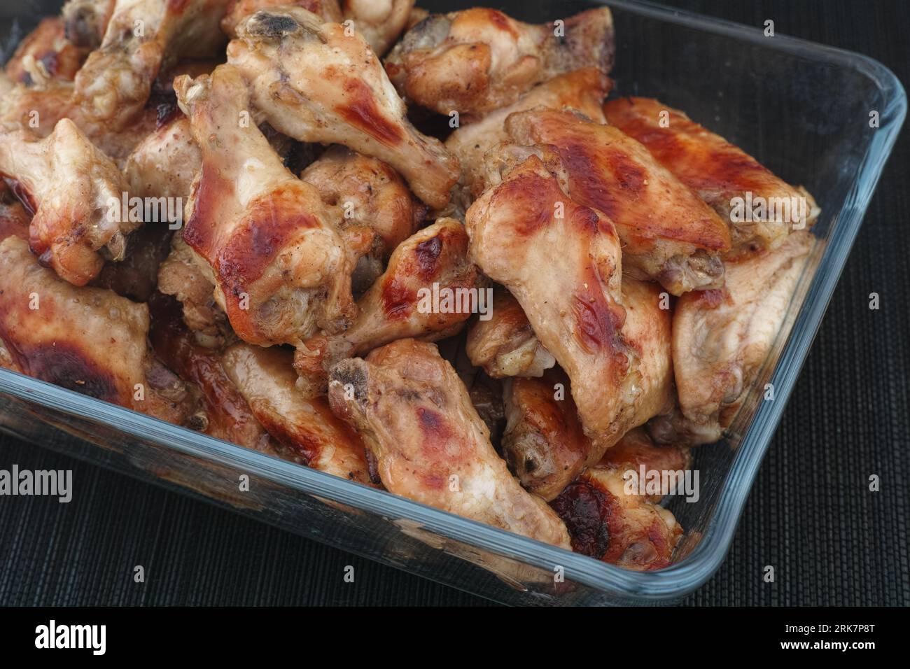 Ali di pollo cotte in un contenitore di vetro. Primo piano. Foto Stock