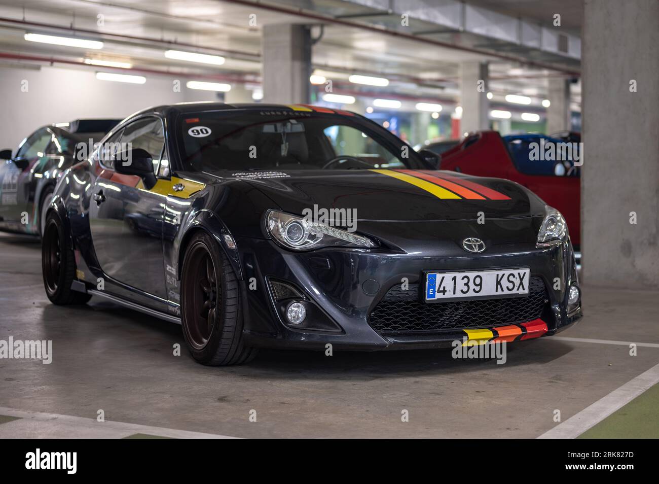 Vista frontale di un'auto sportiva giapponese Toyota GT86 nera con strisce colorate parcheggiata nel parcheggio sotterraneo Foto Stock
