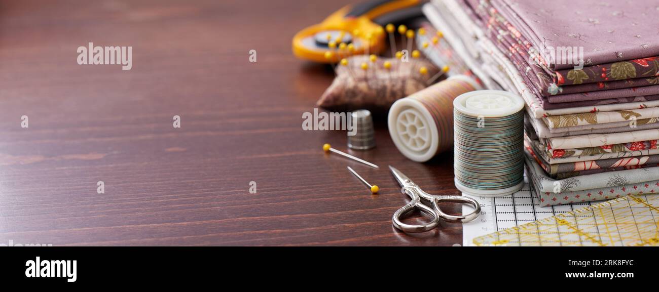 Pila di tessuto per patchwork su tappetino per artigianato, accessori per cucire su superfici in legno Foto Stock