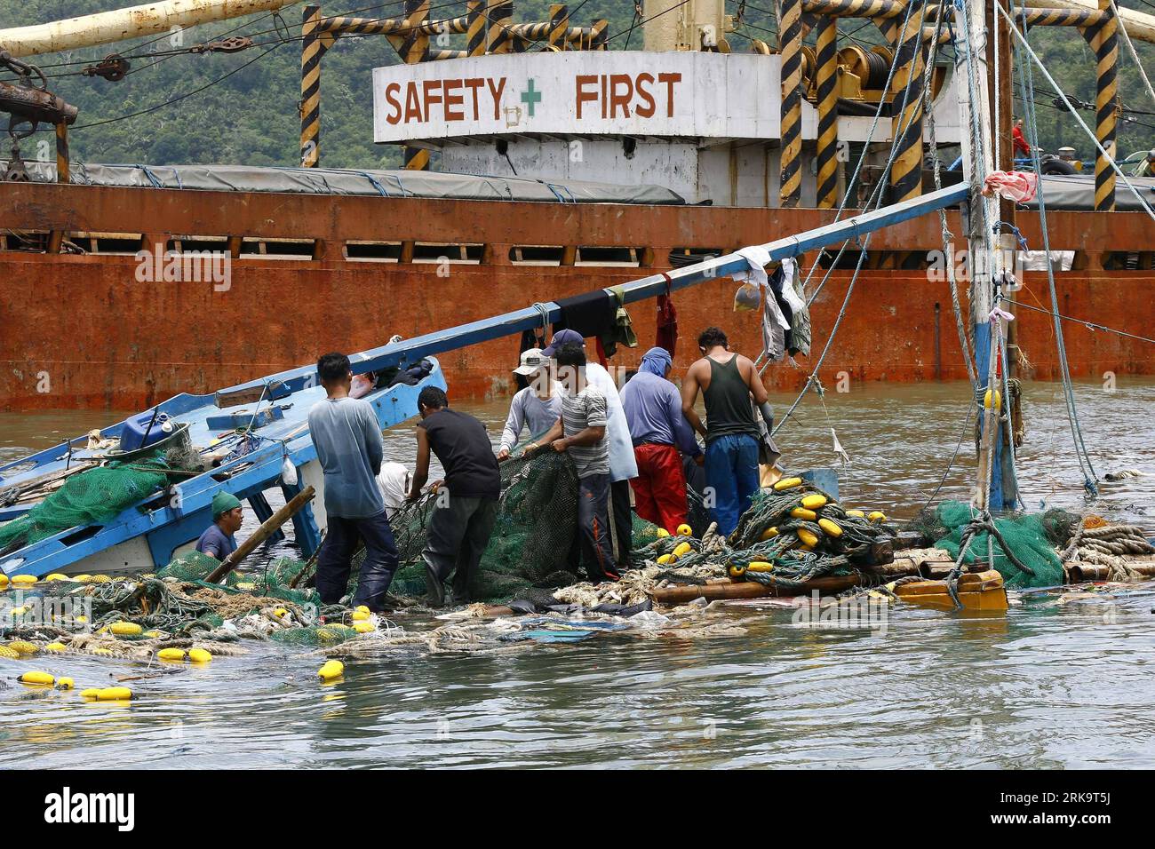 Bildnummer: 54229804 Datum: 15.07.2010 Copyright: imago/Xinhua (100715) -- Manila, 15 luglio 2010 (Xinhua) -- i pescatori cercano attrezzature da pesca utilizzabili da un peschereccio che galleggia sul suo fianco dopo essere sbattuti in una chiatta mentre i corpi di 21 pescatori persi in mare vengono perquisiti dai sommozzatori della Guardia Costiera filippina a Mariveles, Bataan, Filippine, 15 luglio 2010. I corpi dei pescatori sono stati trovati galleggianti nelle acque un giorno dopo che la loro barca da pesca si è capovolta a causa delle grandi onde portate dai forti venti del tifone Conson. (Xinhua/Rouelle Umali) (gj) (7)FILIPPINE-TIFONE CONSON-VITTIME Foto Stock