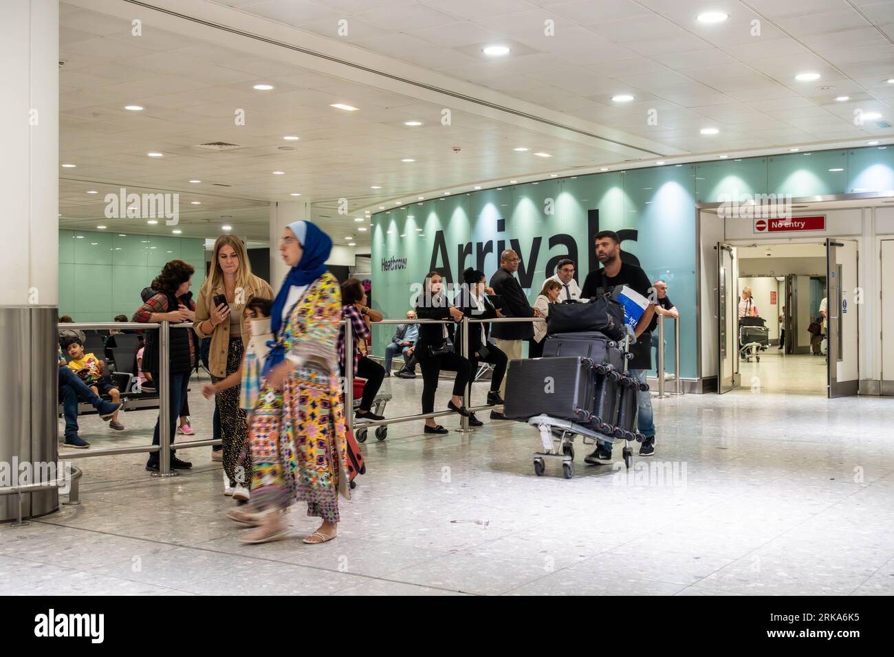 I passeggeri che arrivano al Terminal 3 dell'Aeroporto Heathrow di Londra, passano nella sala degli arrivi Foto Stock