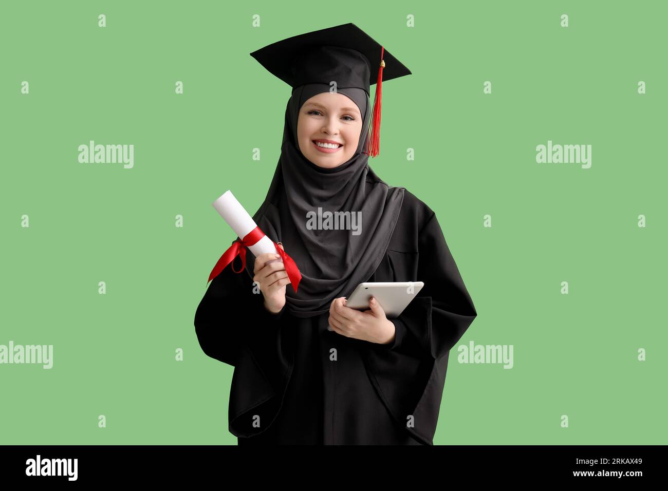 Studente laureato musulmano con diploma e tablet computer su sfondo verde Foto Stock