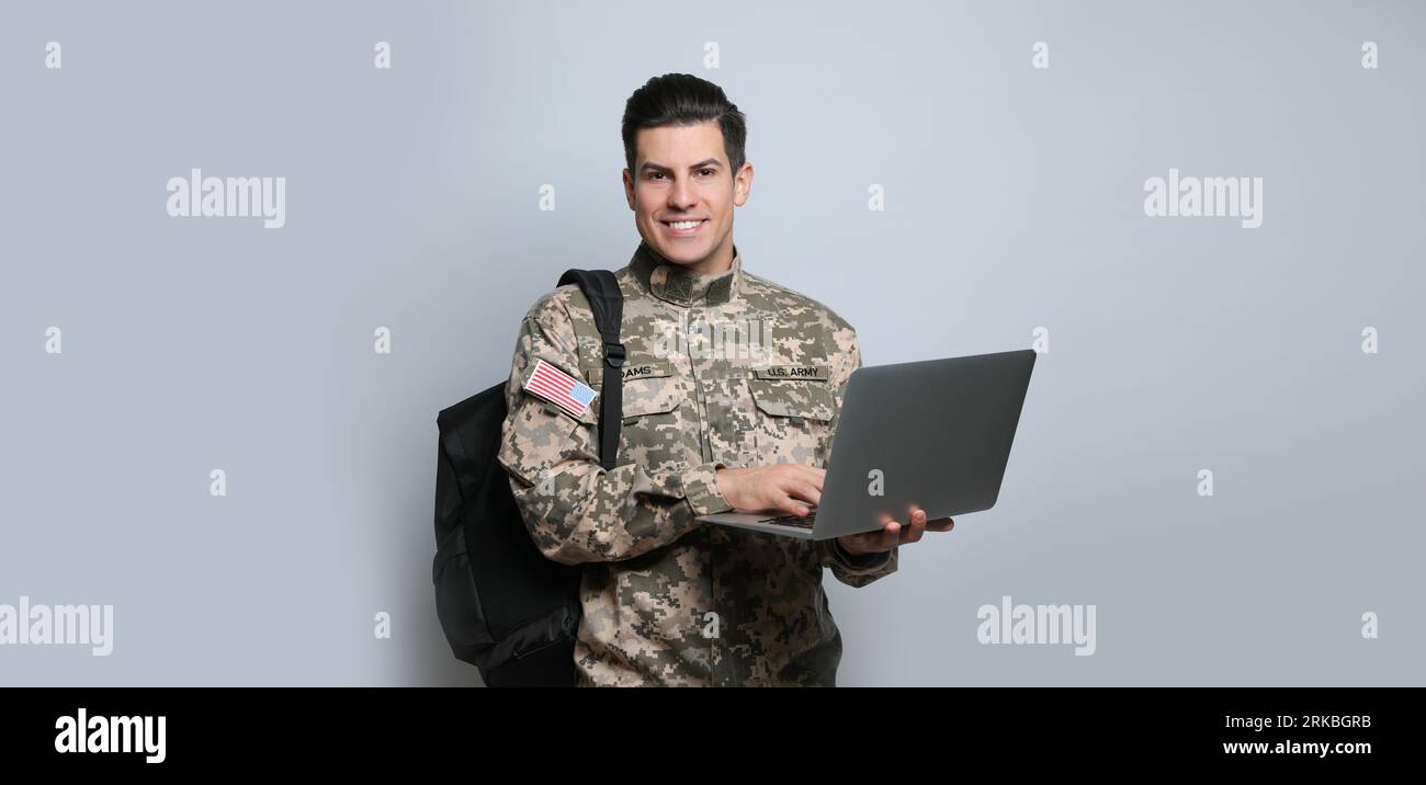 Educazione militare. Cadetto con zaino e laptop su sfondo grigio chiaro Foto Stock