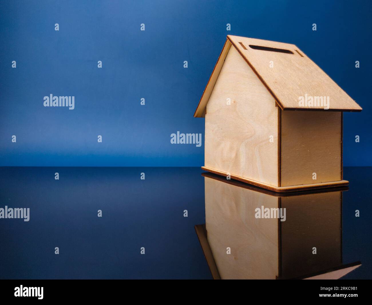 Contenitore in legno per risparmiare denaro con riflesso su un pannello acrilico nero. Concetto aziendale Foto Stock