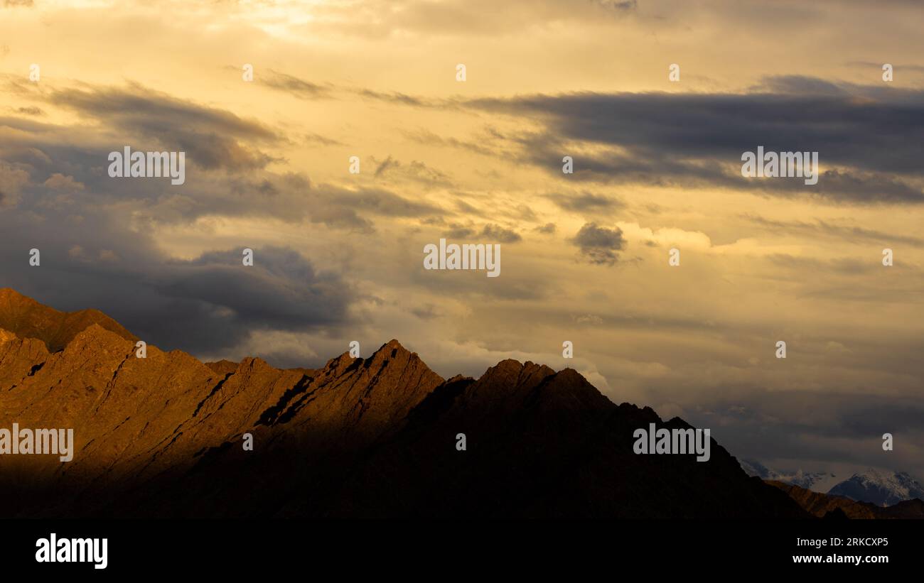 Una vista spettacolare delle montagne con i raggi del sole che cadono tra le nuvole Foto Stock