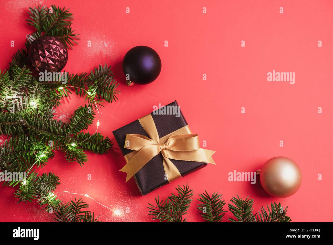 Confezione regalo, palline di Natale colorate e rami di abete con decorazioni natalizie e luci bokeh su sfondo rosso. Vacanze invernali. Vista dall'alto, Foto Stock