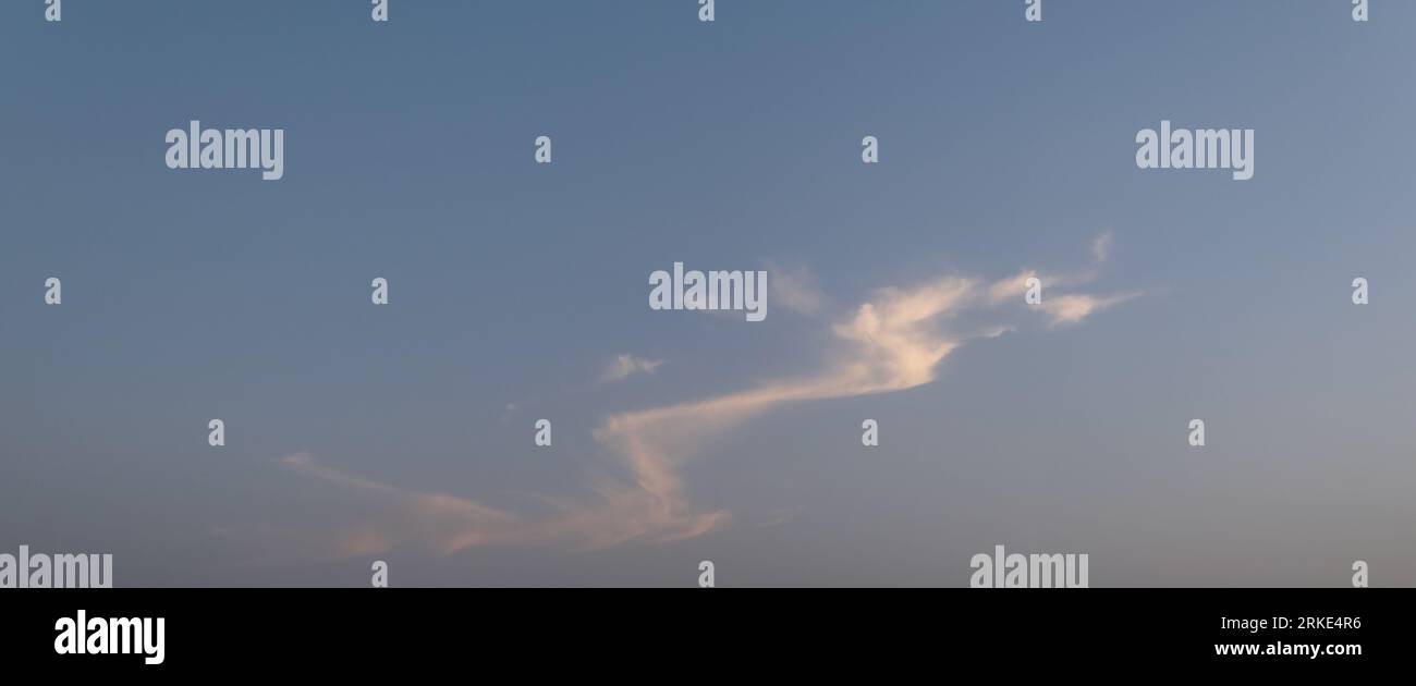 Una foto accattivante cattura il sereno cielo serale mentre il sole discendente bagna il mondo in un caldo bagliore dorato. Le sfumature del cielo dipingono un panorama mozzafiato Foto Stock
