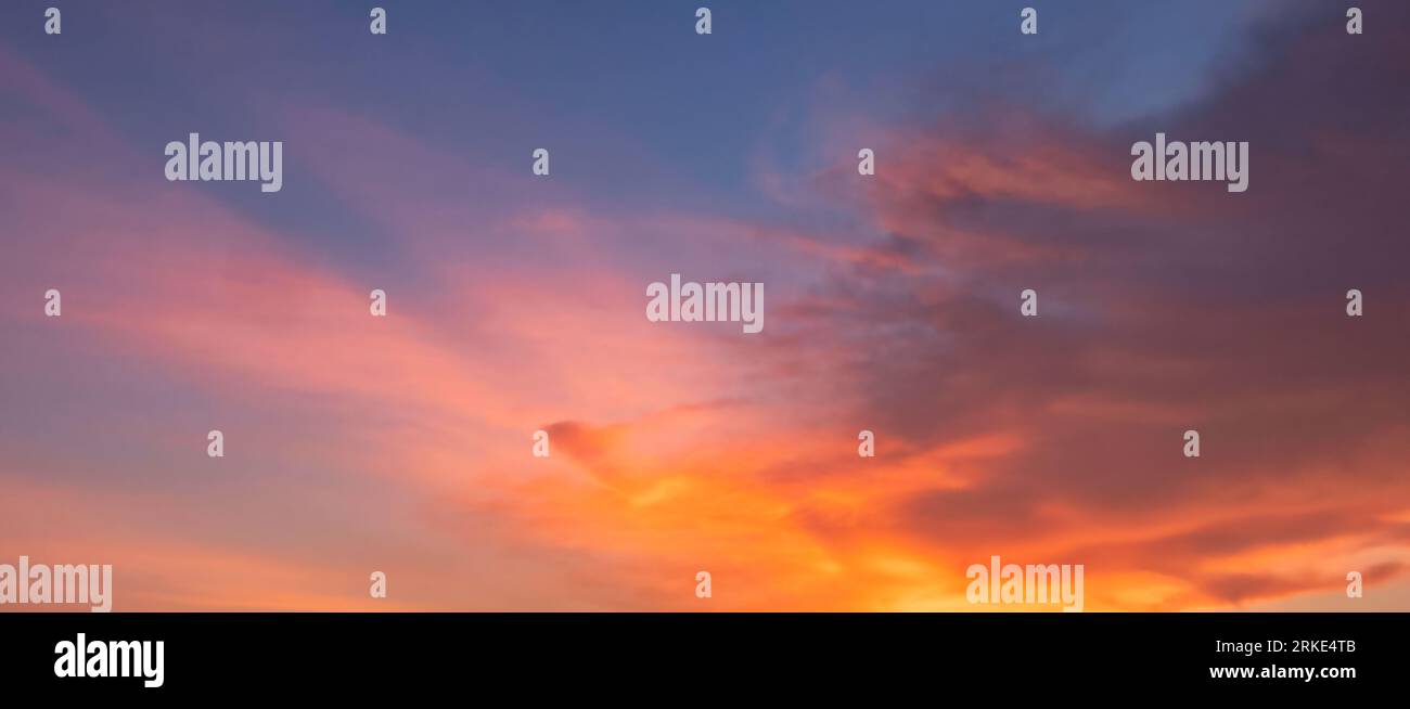 Una foto accattivante cattura il sereno cielo serale mentre il sole discendente bagna il mondo in un caldo bagliore dorato. Le sfumature del cielo dipingono un panorama mozzafiato Foto Stock