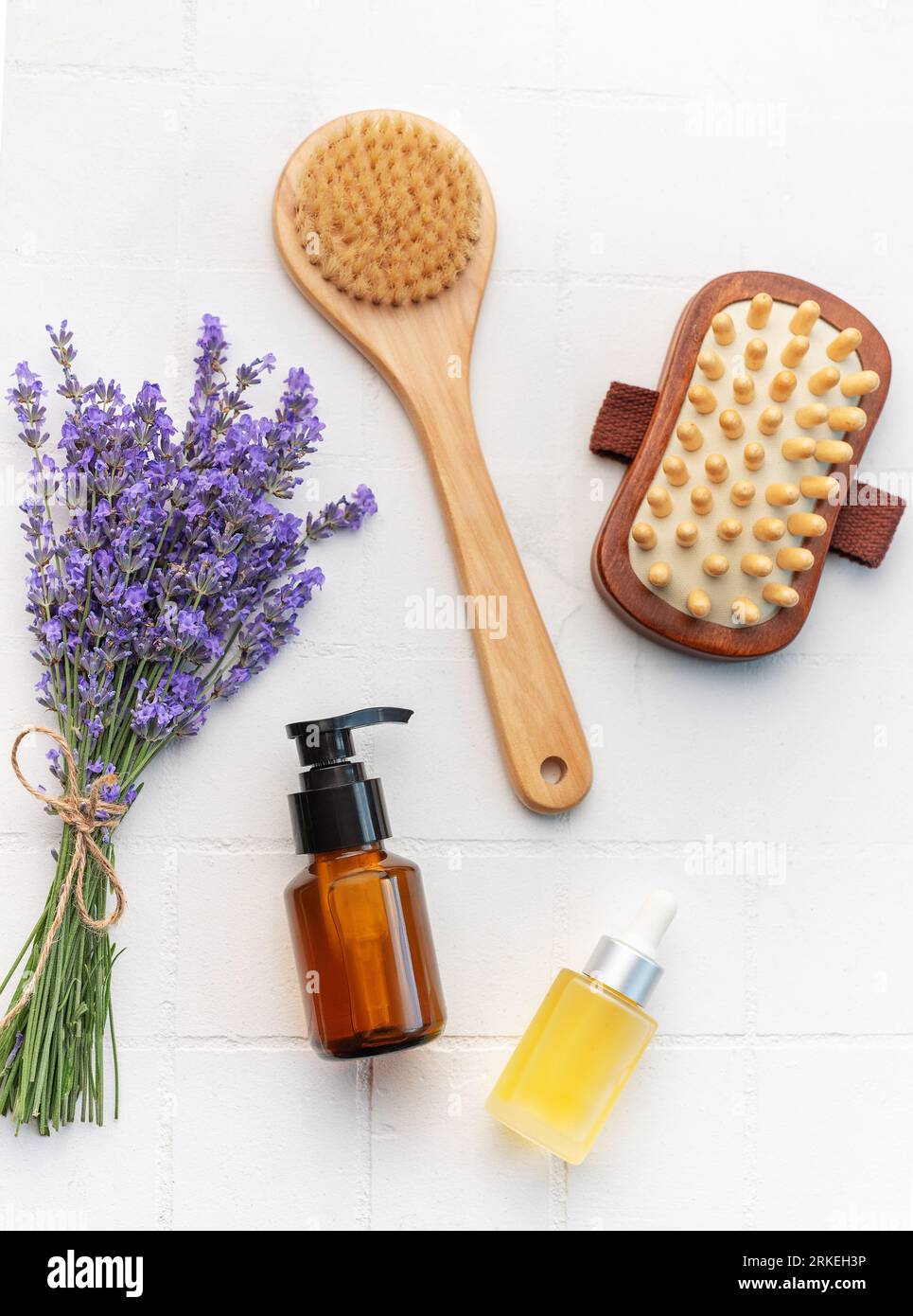 Vasca idromassaggio con lavanda. Sale di lavanda, olio essenziale naturale, spazzole per massaggi e lavanda fresca su fondo di piastrelle bianche. Foto Stock