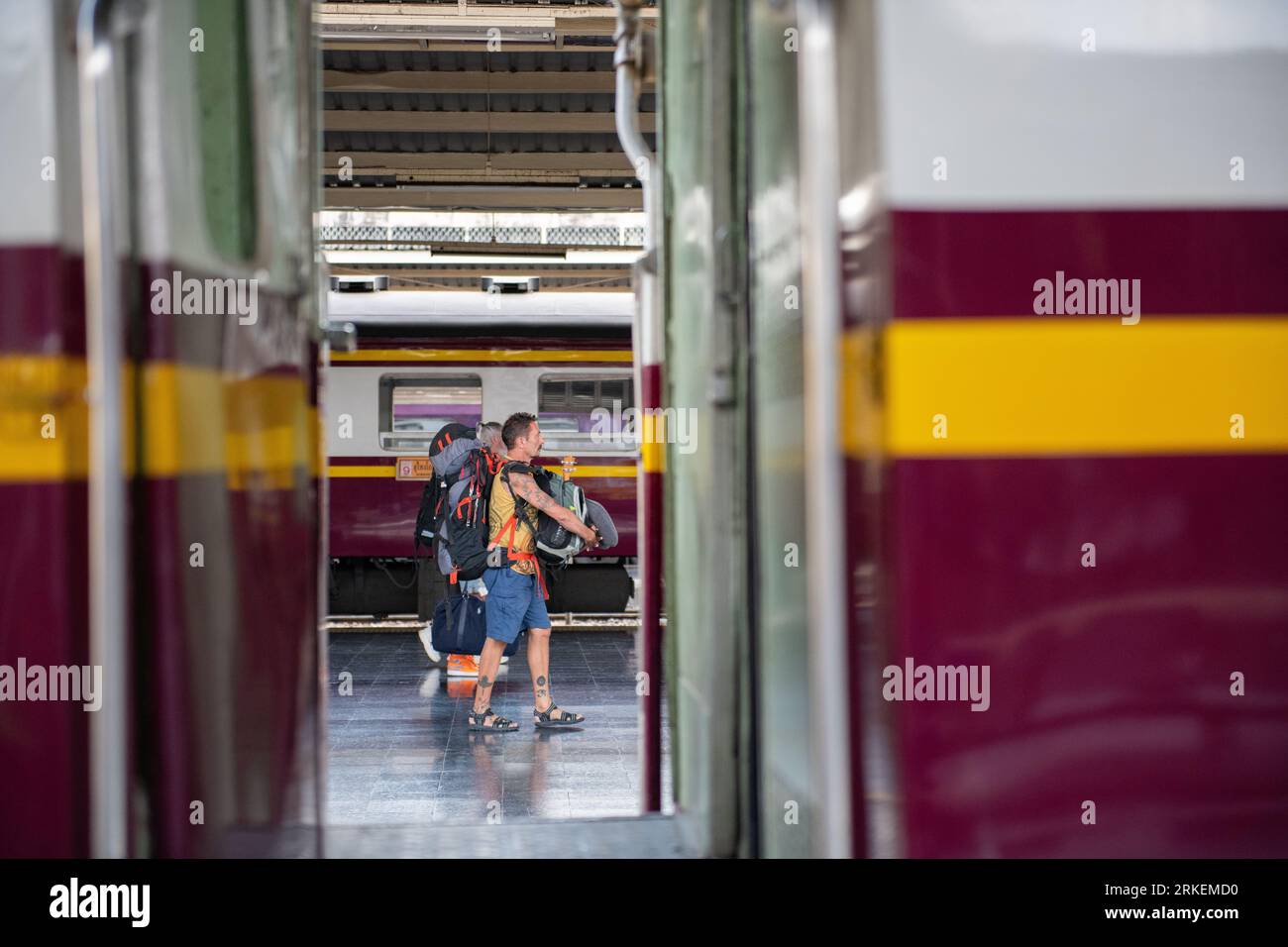 Bangkok, Thailandia: Due viaggiatori con zaino in spalla che camminano attraverso il binario della stazione ferroviaria di Bangkok. Foto Stock