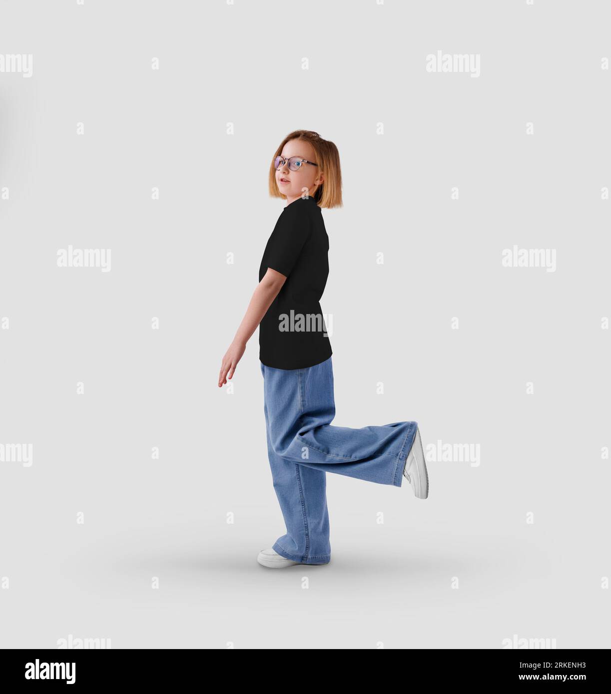 Modello di t-shirt nera per bambini su una ragazza in piena crescita, vista laterale, per design, motivo. Mockup camicia testurizzata isolato sullo sfondo. Fot. Prodotto Foto Stock