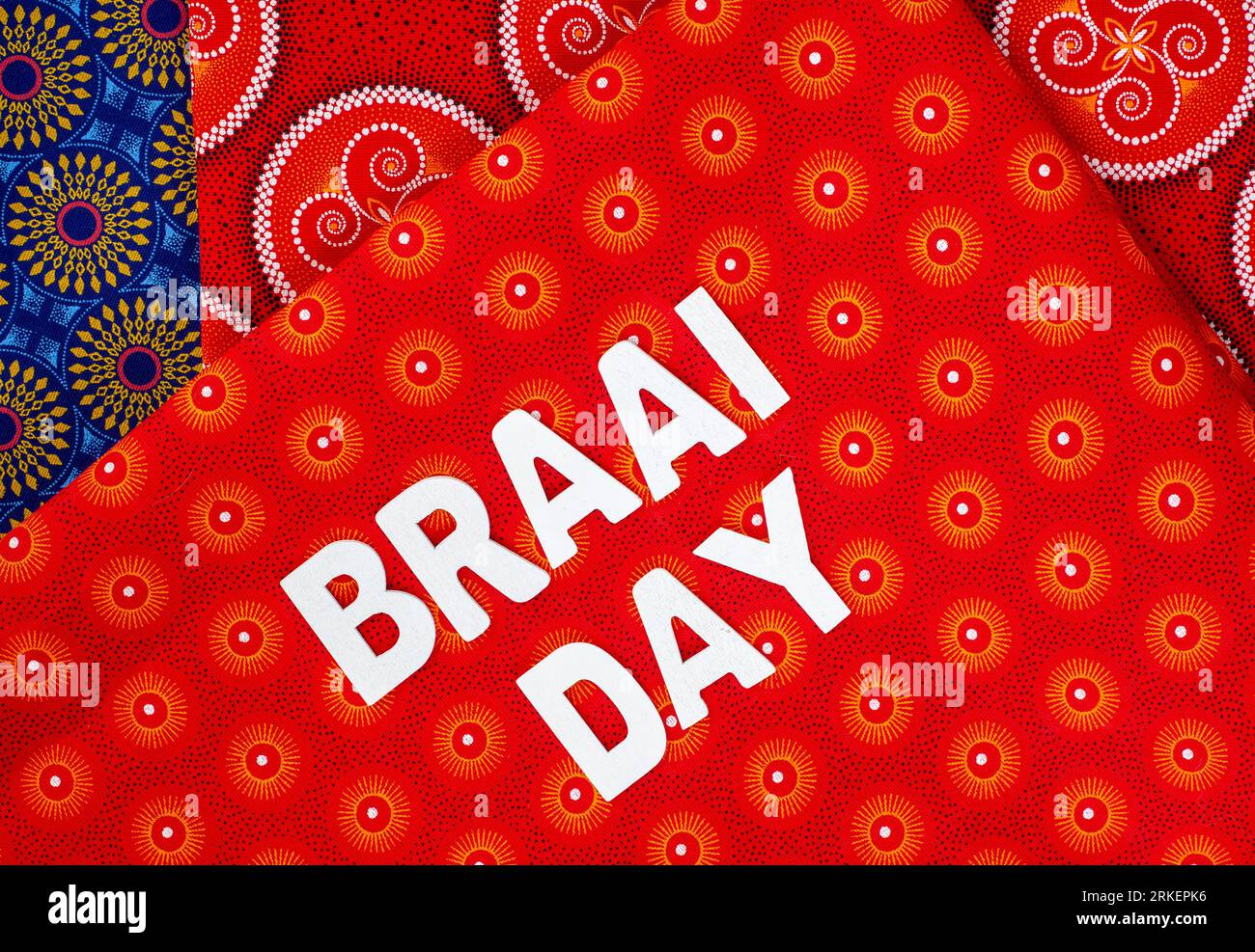 Heritage Day Sudafrica. Braai Day scritto in lettere bianche con l'iconico tessuto stampato sudafricano Foto Stock