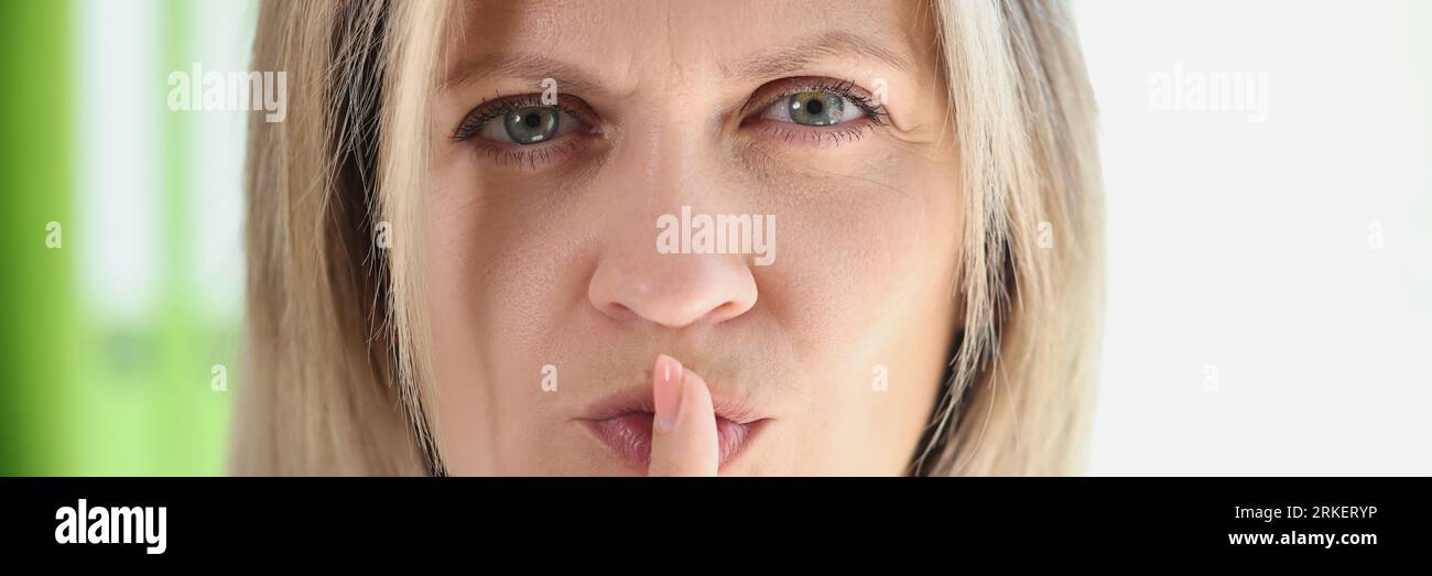 Donna con faccia seria tiene il dito sulle labbra e chiede silenzio. Foto Stock