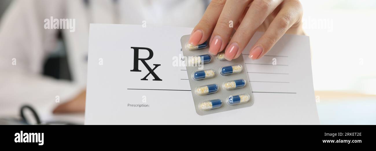 Il medico femminile mostra in bianco carta da prescrizione e pillole mediche. Foto Stock