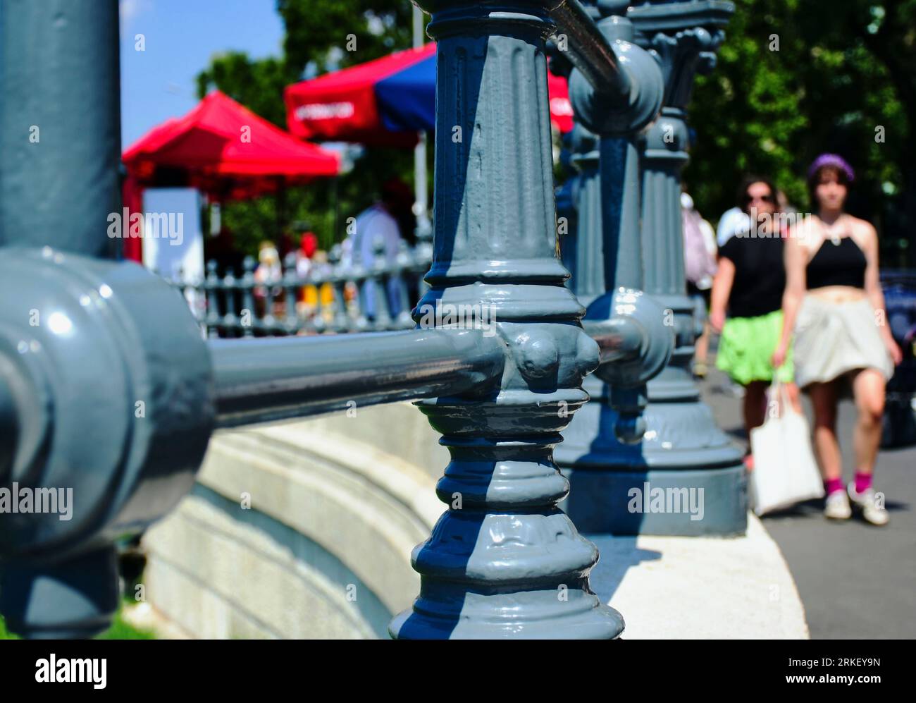 ringhiera in ghisa grigia lungo il marciapiede pubblico in asfalto. passaggio di pedoni sfocati. base in pietra. Scena estiva sulla famosa strada urbana di Budapest Foto Stock